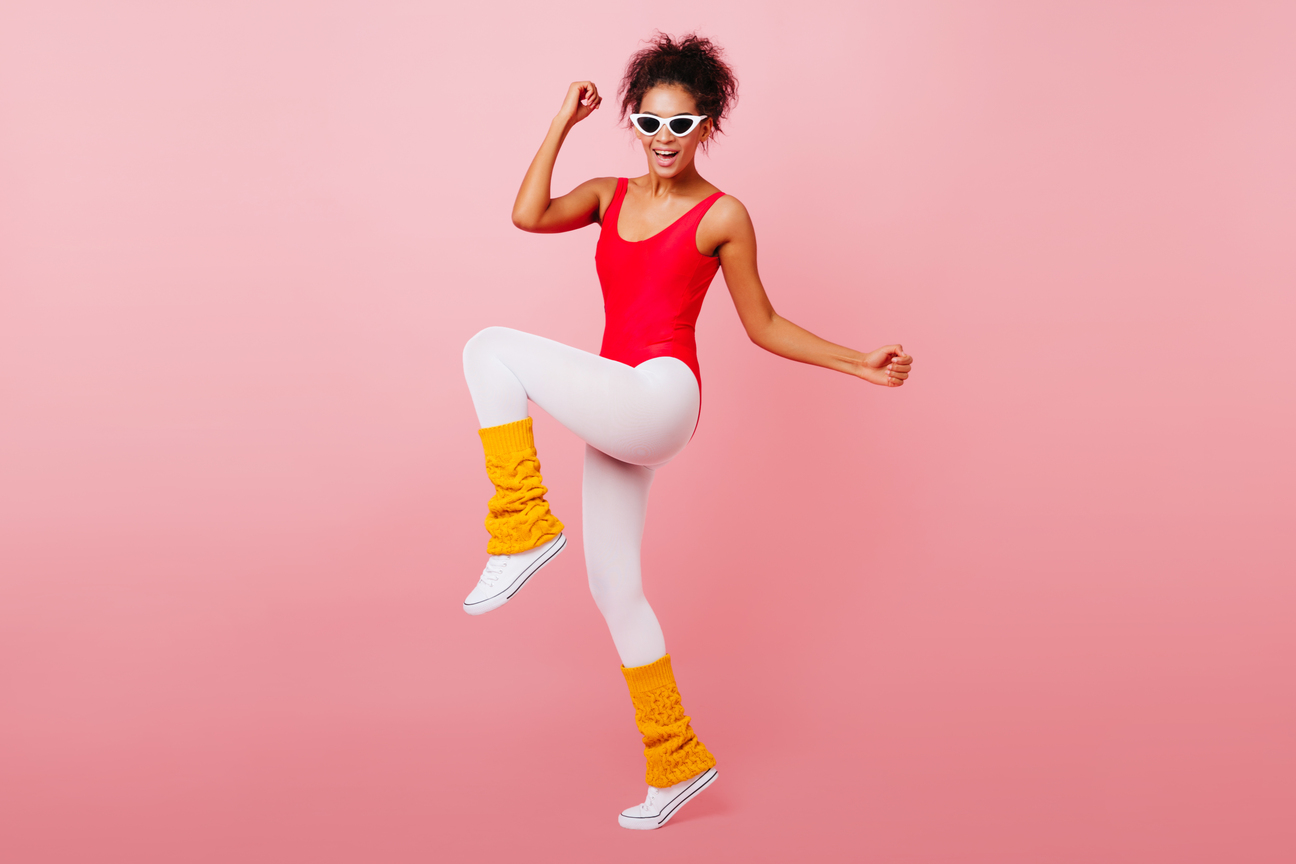 Stunning black girl dancing with smile on pink background. Gorgeous african woman doing aerobics.